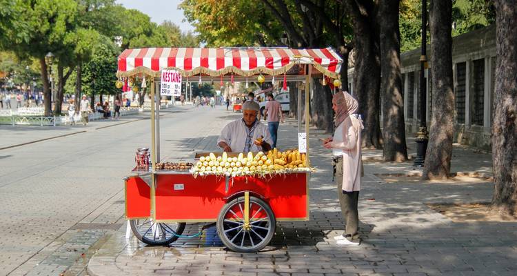 Vendeur de rue avec chariot dans un cadre urbain.