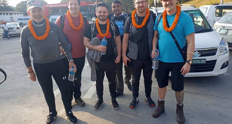 Groupe de personnes portant des guirlandes, debout dans une zone de stationnement.
