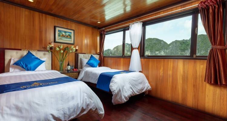 Twin beds in a wooden interior cabin with a large window.