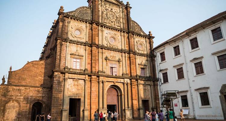 Façade de la basilique historique en pierre rouge de Bom Jesus sous un ciel dégagé avec des visiteurs à l'extérieur