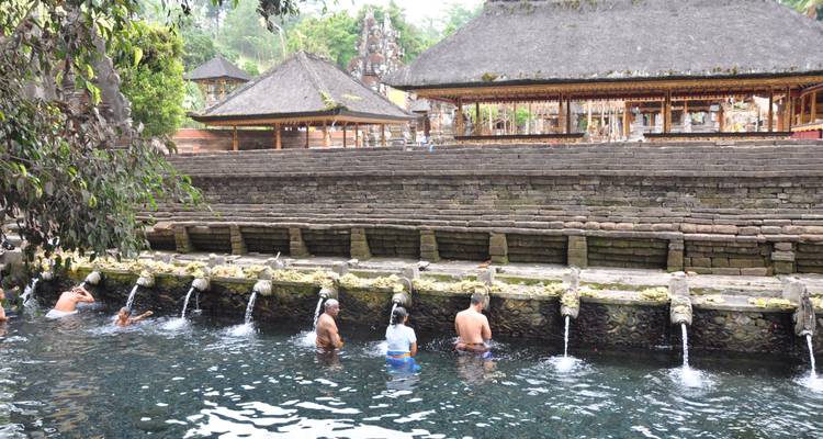 Des gens se baignant dans une source sacrée dans un cadre de temple traditionnel.