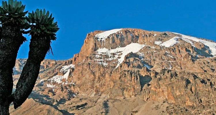 Paisaje de montañas rocosas con nieve en la cima.