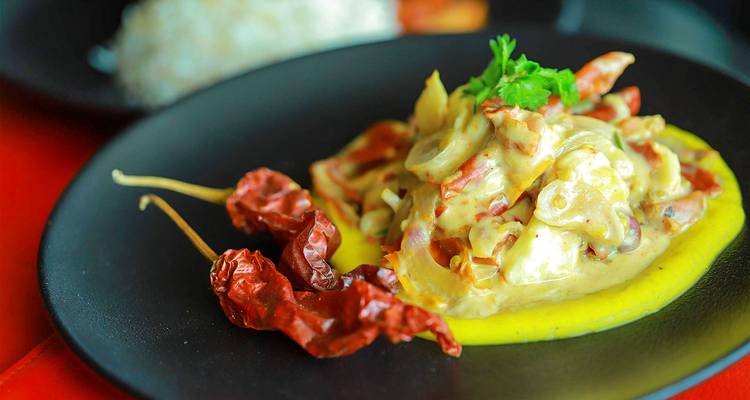 Teller mit bhutanischem Essen einschließlich getrockneter Chilis und einem cremigen Gericht.