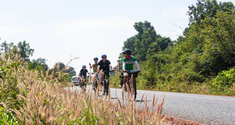 Cyclistes roulant sur une route rurale sous un ciel dégagé.