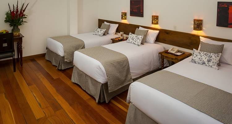 Een hotelkamer interieur met drie netjes opgemaakte bedden en warme decoratie.