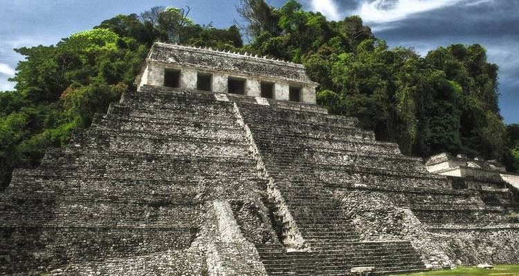 Pyramide de pierre spectaculaire de Palenque encadrée par une jungle luxuriante sous un ciel chargé.