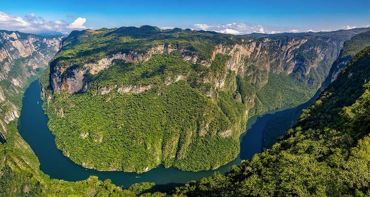 Vue aérienne panoramique du canyon sinueux de Sumidero avec des parois verticales luxuriantes entourant une rivière d'un vert émeraude profond.