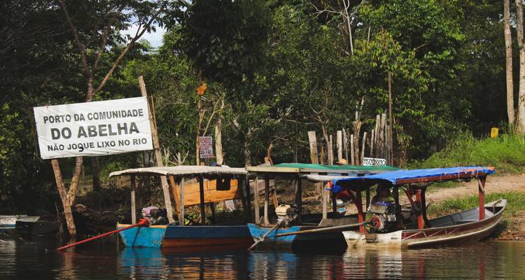 Zona de muelle con botes sencillos cerca de un letrero rústico de la comunidad.