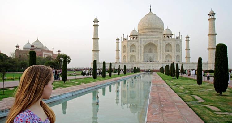 Le Taj Mahal avec une personne au premier plan, se reflétant dans l'eau.