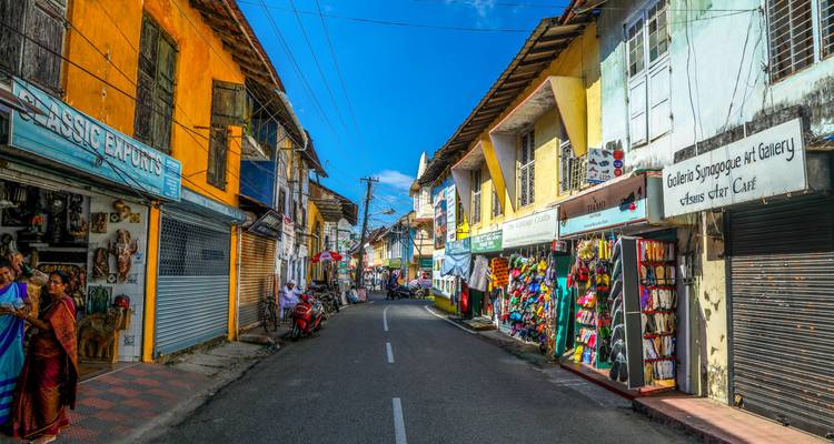 Levendige straat met winkels en een heldere blauwe lucht.