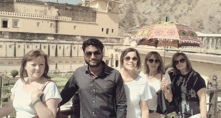 Touristen posieren vor einer historischen Festung mit einem bunten Regenschirm.