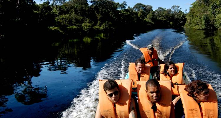 Groupe de personnes naviguant sur une rivière entourée d'une jungle dense.