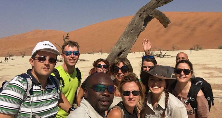 Grupo de personas posando en un paisaje desértico con dunas.