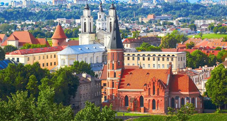 Vista panorámica sobre iglesias de techos rojos y edificios históricos de Kaunas rodeados de vegetación.