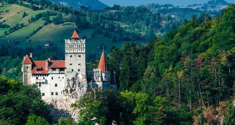 Le château de Bran, perché sur un affleurement rocheux entouré par une forêt de Transylvanie dense et des collines ondulantes.