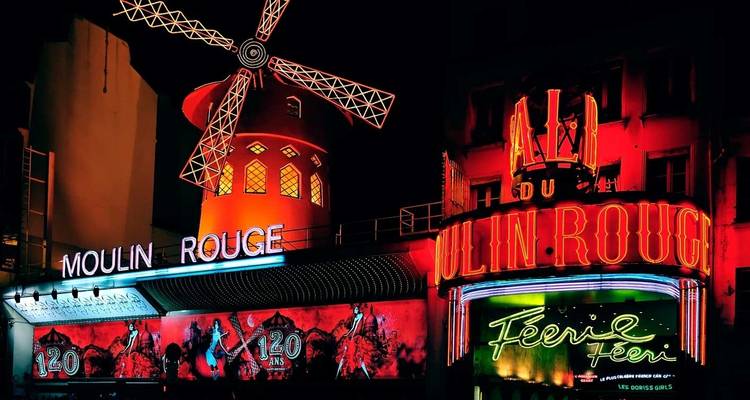 Nachtelijke neongloed van het Moulin Rouge cabaret met zijn iconische rode windmolen in Parijs.