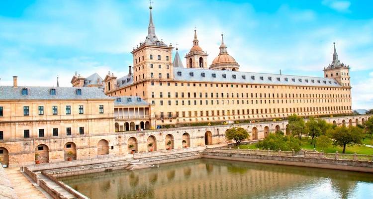 The grand El Escorial monastery-palace complex reflected in its ornamental pool beneath a bright sky.