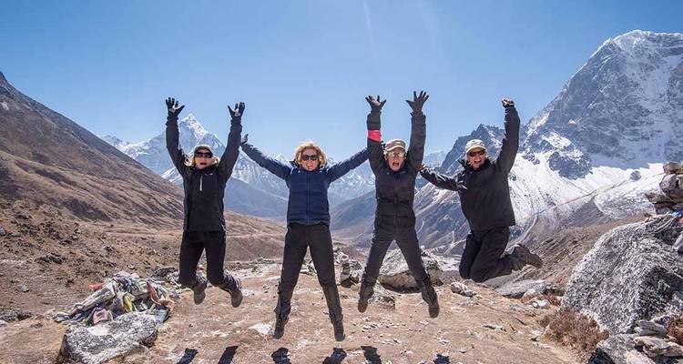 Groupe de randonneurs sautant avec un décor de montagne enneigée.