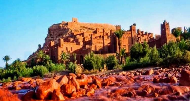 Ait Benhaddou, een historisch versterkt dorp in een schilderachtig landschap met een rivier op de voorgrond.