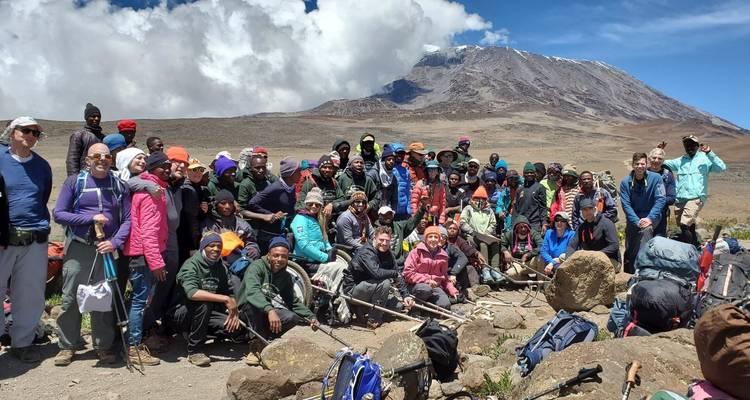 Gran grupo de excursionistas posando en una montaña con cielos despejados.