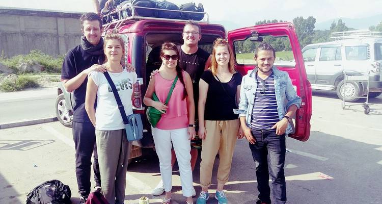 Eine Gruppe von Touristen, die bei einem geparkten roten Van stehen.