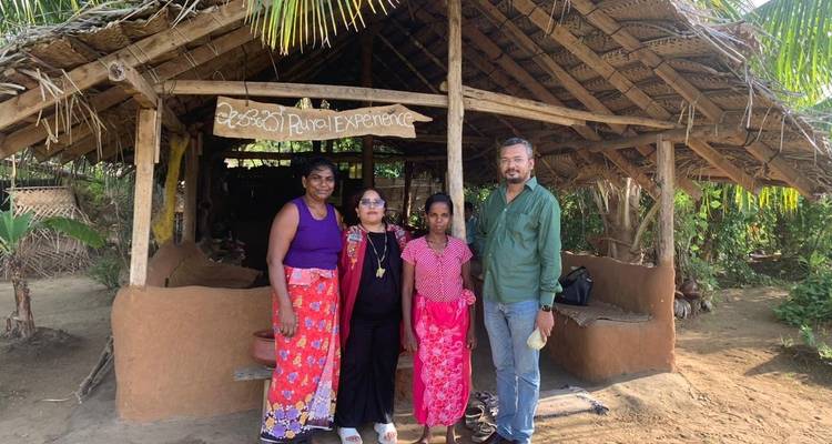 Four people posing in front of a rustic structure with a 'Rural Experience' sign.