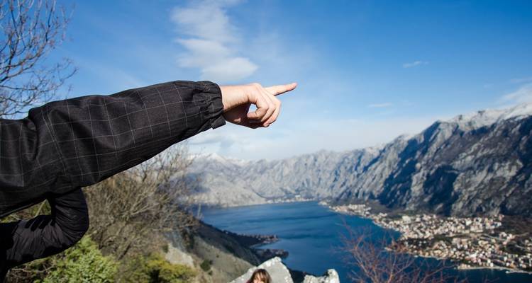 Arm die wijst naar een schilderachtig kustgezicht.
