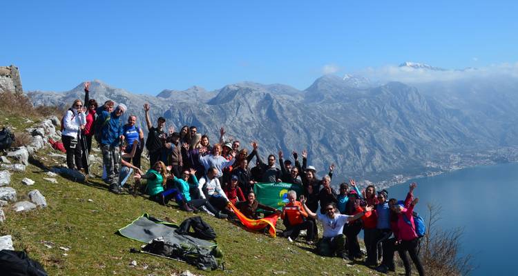 Grote groep poseert met een schilderachtig berglandschap op de achtergrond.