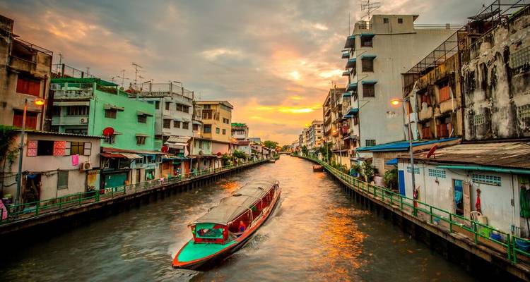 Canal with colorful boats and buildings during sunset.