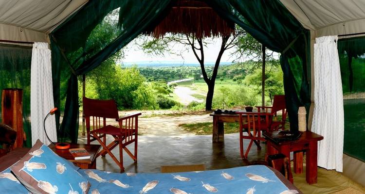 Interieur van een safaritent met uitzicht op het landschap buiten.