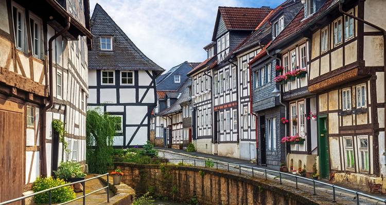 A narrow canal flanked by rows of colourful timber houses in a peaceful medieval quarter.