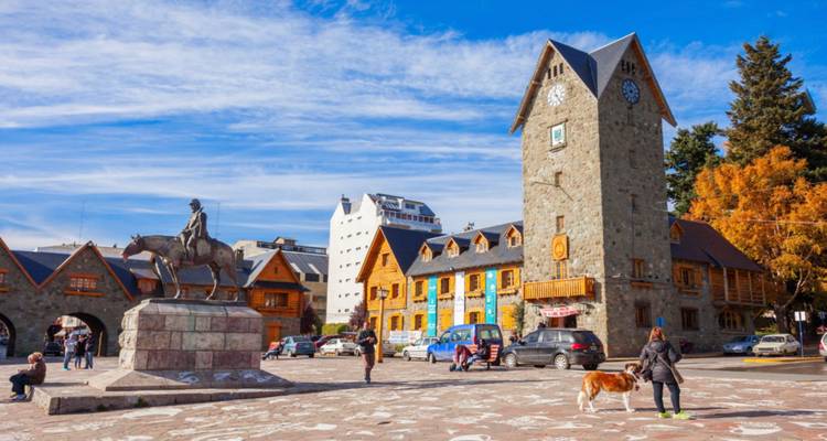 Torre de reloj de piedra y árboles de otoño dominan la plaza del centro cívico de San Carlos de Bariloche