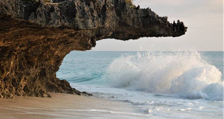 Rocky coastline with a wave crashing against a cliff.
