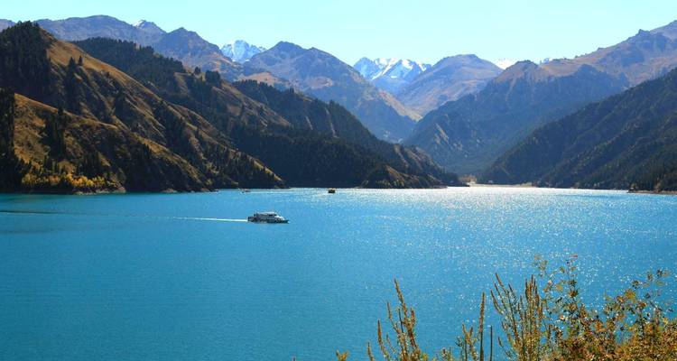 Een schilderachtig meer omringd door bergen met een boot op het water.
