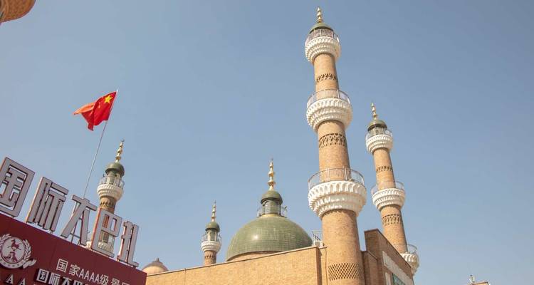 Moskee met hoge minaretten en een Chinese vlag onder een heldere blauwe hemel.