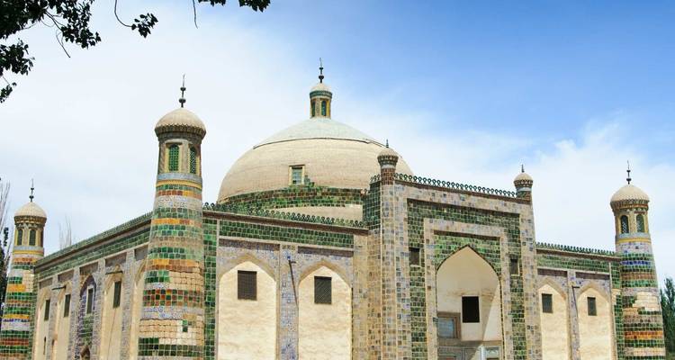 Decoratieve moskee met groene tegels en koepels onder een heldere hemel.