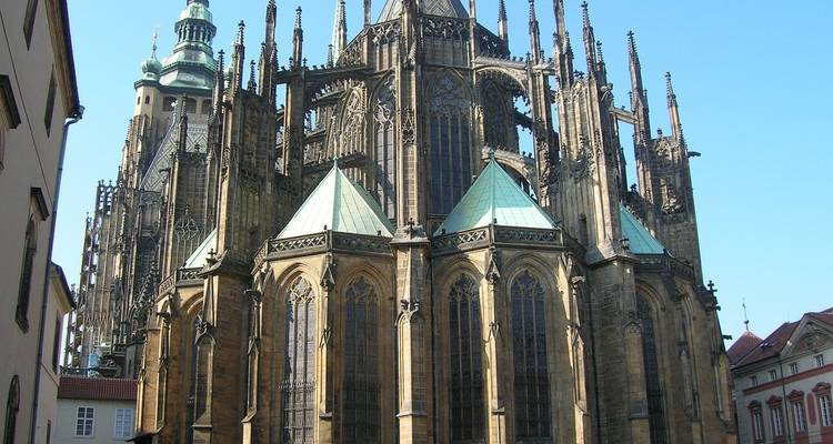 Close-up of the soaring Gothic buttresses and spires of St. Vitus Cathedral against a clear sky.