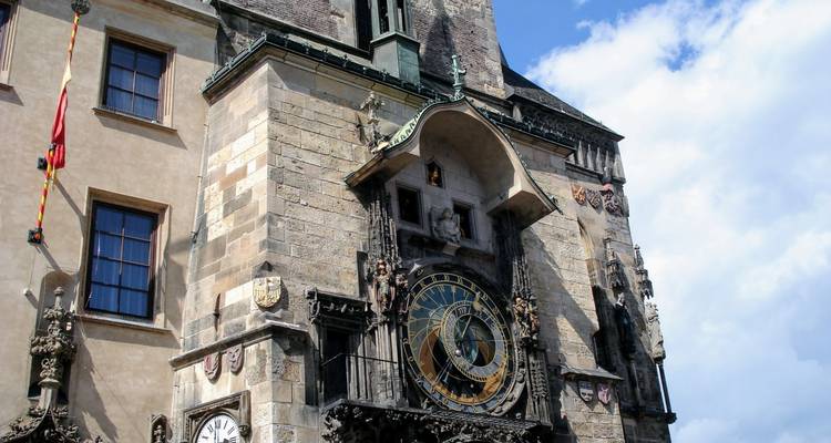 Detail of Prague’s Astronomical Clock on the Old Town Hall, showing ornate stonework and gilded dial against a blue sky.