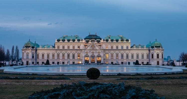 Elegant Belvedere Palace reflected in a sweeping pool under a soft blue twilight sky.