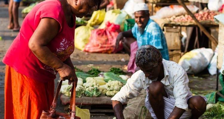 Des gens qui achètent et vendent des légumes dans un marché en plein air.