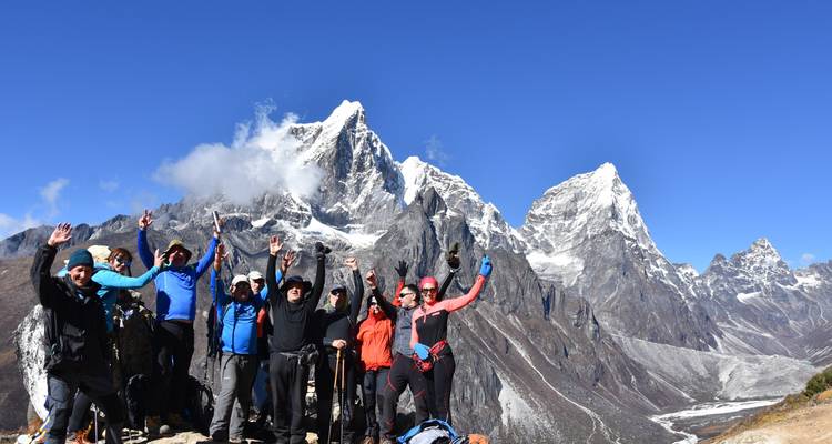 Groep trekkers met besneeuwde bergen op de achtergrond.