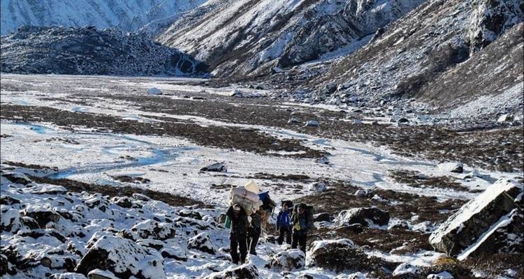 Wanderer, die durch ein schnebedecktes Tal gehen.