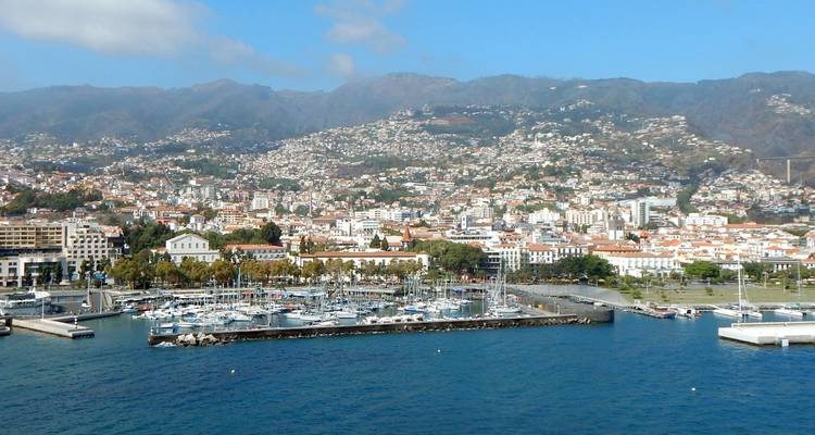 Vue sur le port avec paysage urbain adjacent sur fond de montagnes.