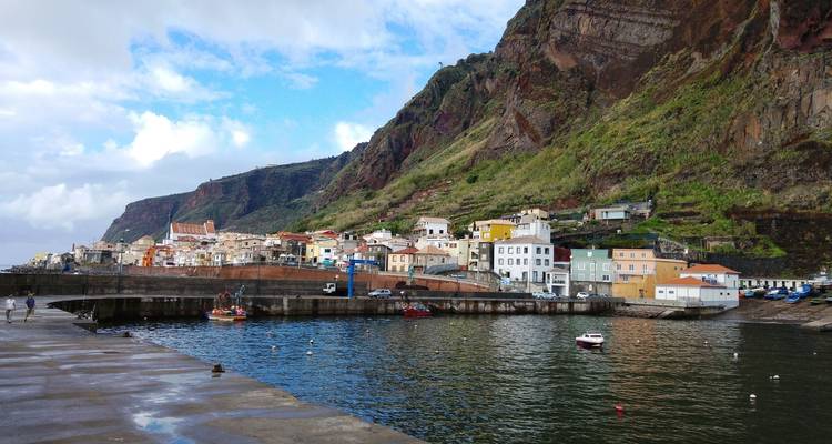 Pueblo costero enclavado contra montañas rocosas.