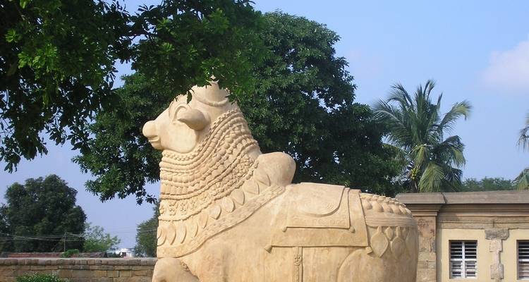 Groot gebeeldhouwd standbeeld van Nandi met bomen op de achtergrond.