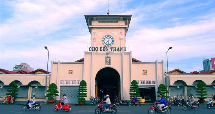 Marktszene mit Menschen und Motorrädern vor einem Marktgebäude.