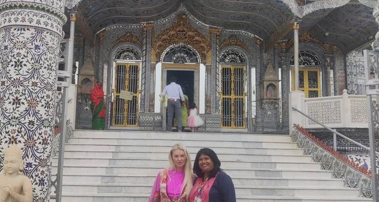 Zwei Frauen posieren auf den Stufen eines verzierten Tempeleingangs.