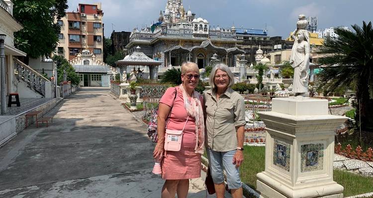 Zwei Frauen posieren vor einem kunstvoll verzierten Tempelgarten.