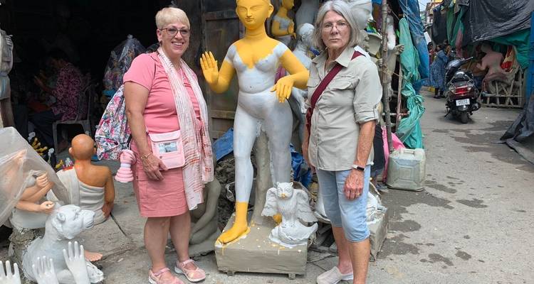 Zwei Frauen posieren mit unfertigen Tonskulpturen.