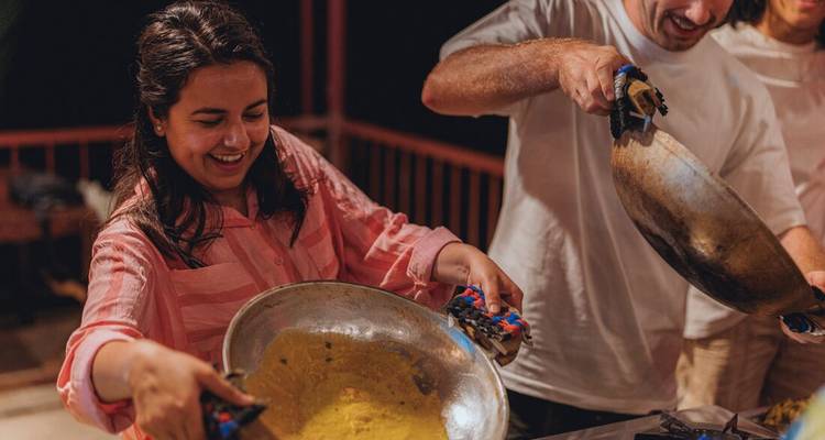 Un participant rit en remuant les ingrédients pendant un cours de cuisine pratique.